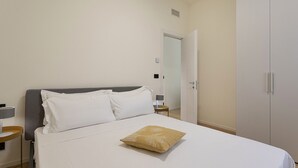 Una habitación de hotel con cama, mesita de noche, lámpara y armario.