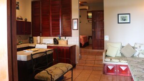 A compact living space with a kitchen area, a dining table, and a sofa with cushions.