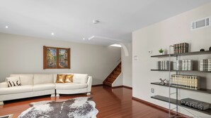 A modern living room with a white sofa, a leather rug, a bookshelf with books, and a painting on the wall. - Lansdale: Work, Rest, Explore (Lansdale)