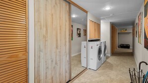 A laundry room with a washing machine and dryer, wooden sliding doors, and a hallway with artwork on the walls. - Lansdale: Work, Rest, Explore (Lansdale)