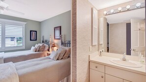 A bedroom with two beds, a vanity with a mirror and lights, and a ceiling fan. - Harbour Oaks 312 - 2Br/2Ba condo near Village (St. Simons Island)