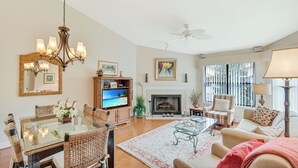 A spacious living room with a fireplace, a dining area with a glass table, and a cozy seating area with a sofa and armchairs. - Harbour Oaks 312 - 2Br/2Ba condo near Village (St. Simons Island)