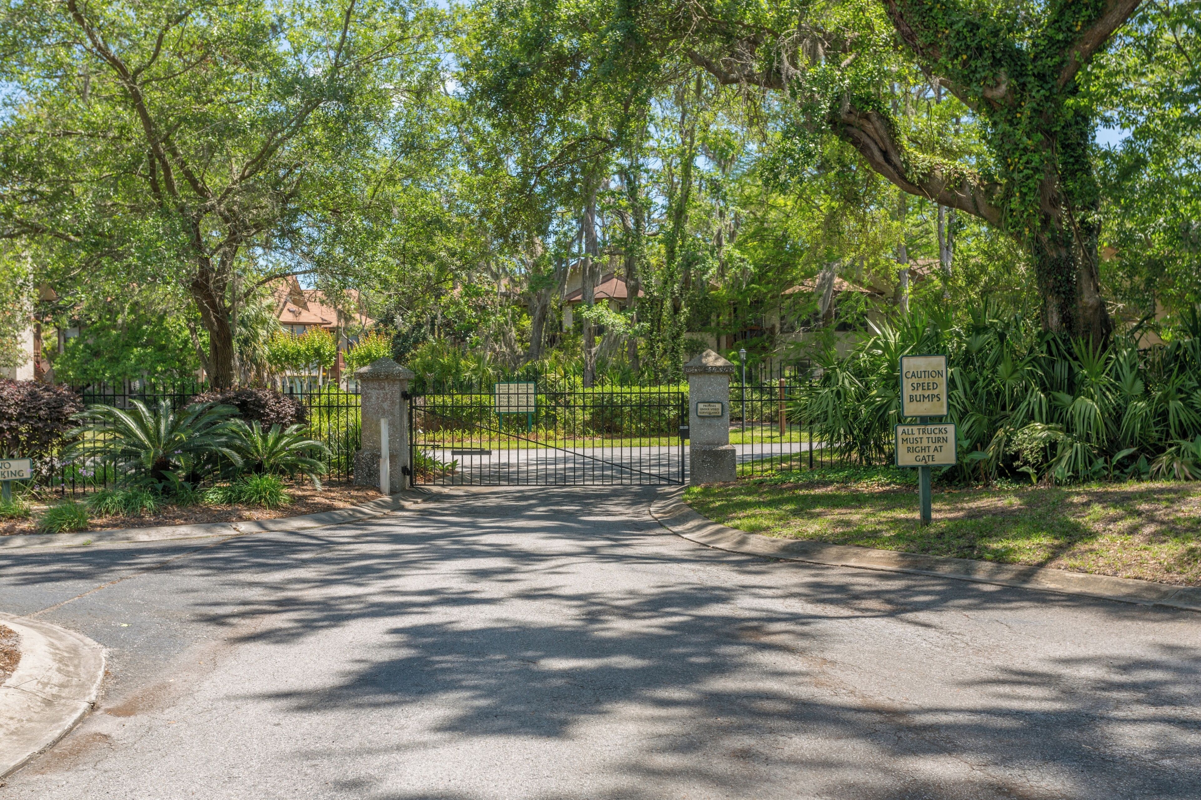 A gated entrance with a sign warning of speed bumps and a requirement for trucks to turn right.