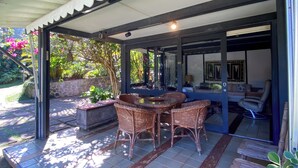 A covered patio area with a table and chairs, a seating area with a sofa and armchairs, and a view of the garden. - Spectacular Farm in Ibiúna (Ibiuna)