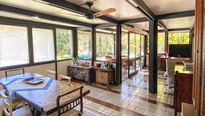 A spacious room with a large dining table, chairs, and a television. There are windows providing natural light and a view of the outdoors. - Spectacular Farm in Ibiúna (Ibiuna)