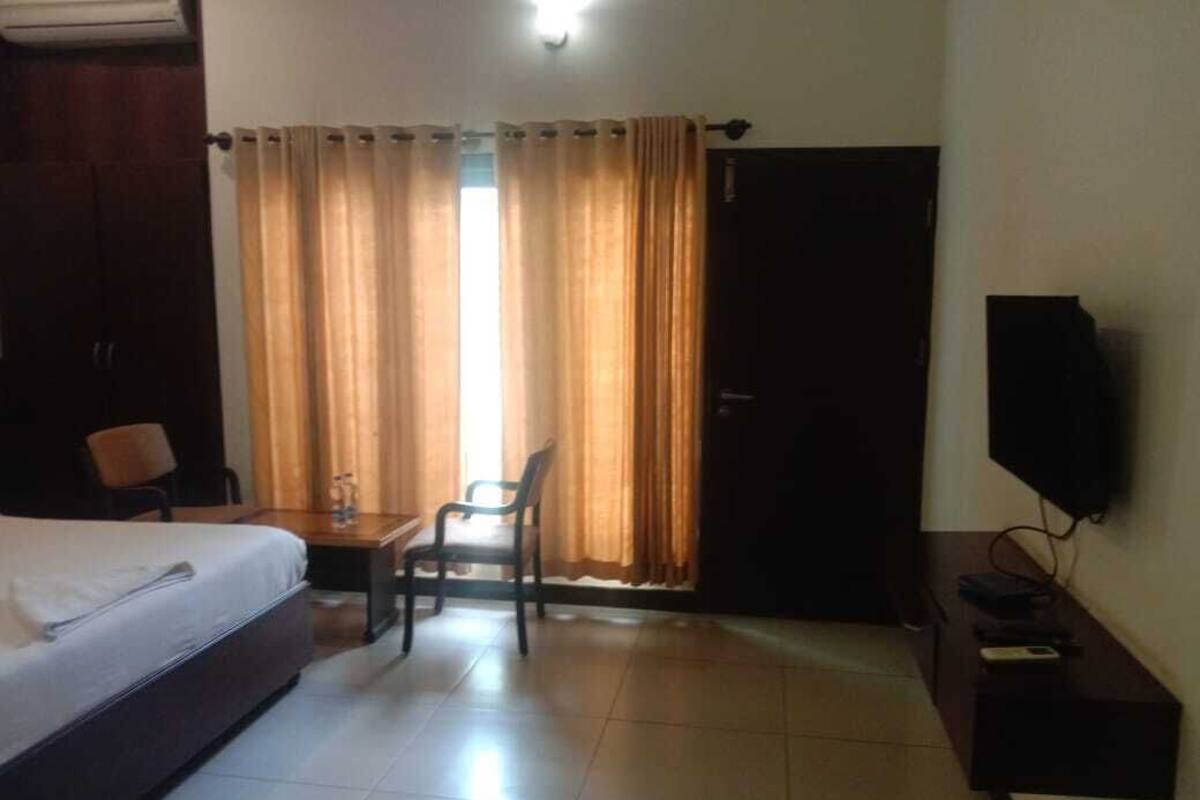 A hotel room with a bed, a desk, a chair, a television, and a door.
