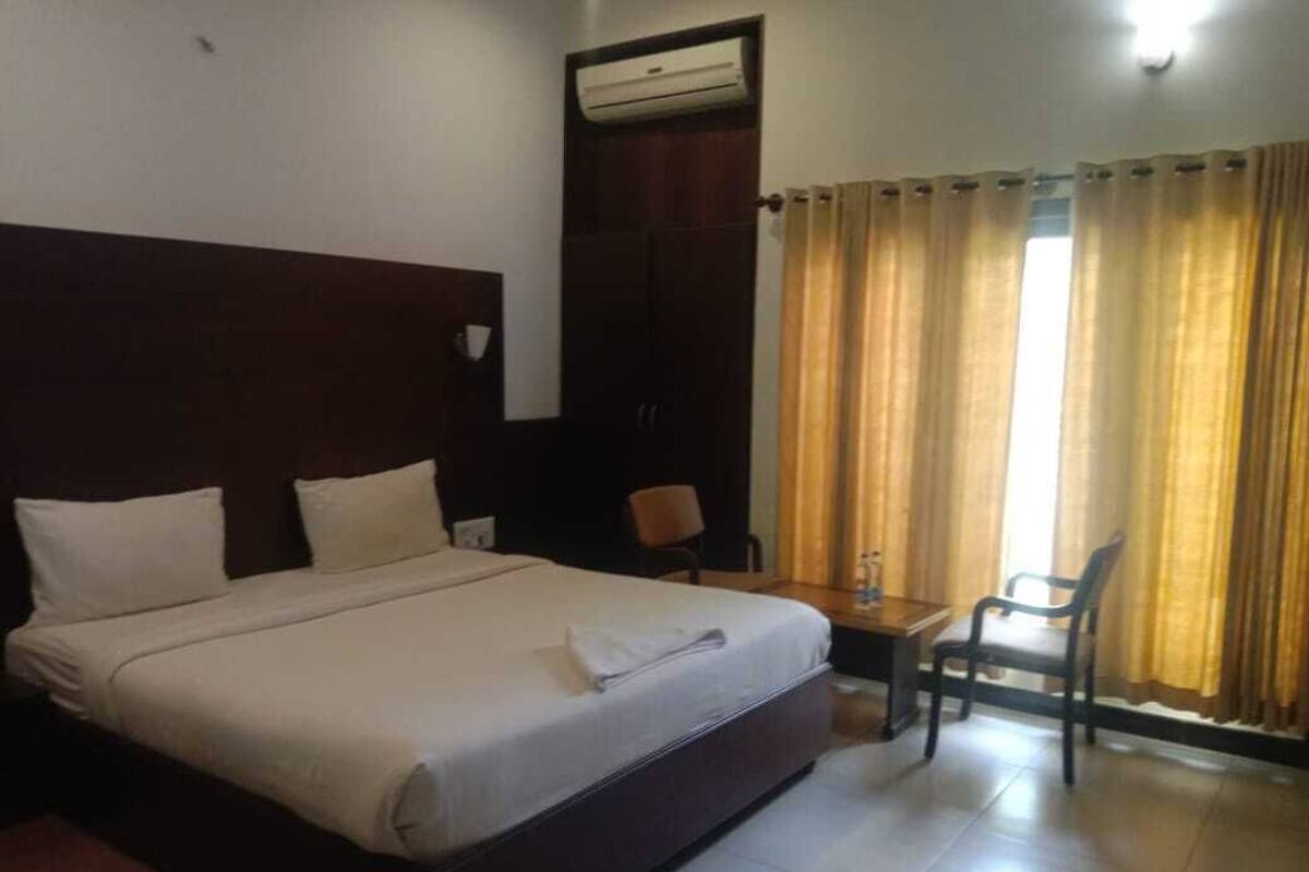 A hotel room with a large bed, a desk, a chair, and a wardrobe.