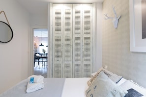 A bedroom with a bed, a white wall, a wooden door with shutters, and a mounted deer head. - Astoria - baskeyrentals (San Sebastián)