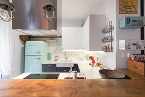 A modern kitchen with a light blue refrigerator, white cabinets, and a wooden countertop. - Astoria - baskeyrentals (San Sebastián)