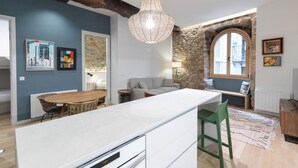 A modern kitchen with a central island, a stone wall, and a large window. - Zutabe - baskeyrentals (Azpeitia)