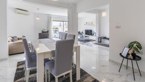 A modern living room with a dining area, a sofa, and a TV.
