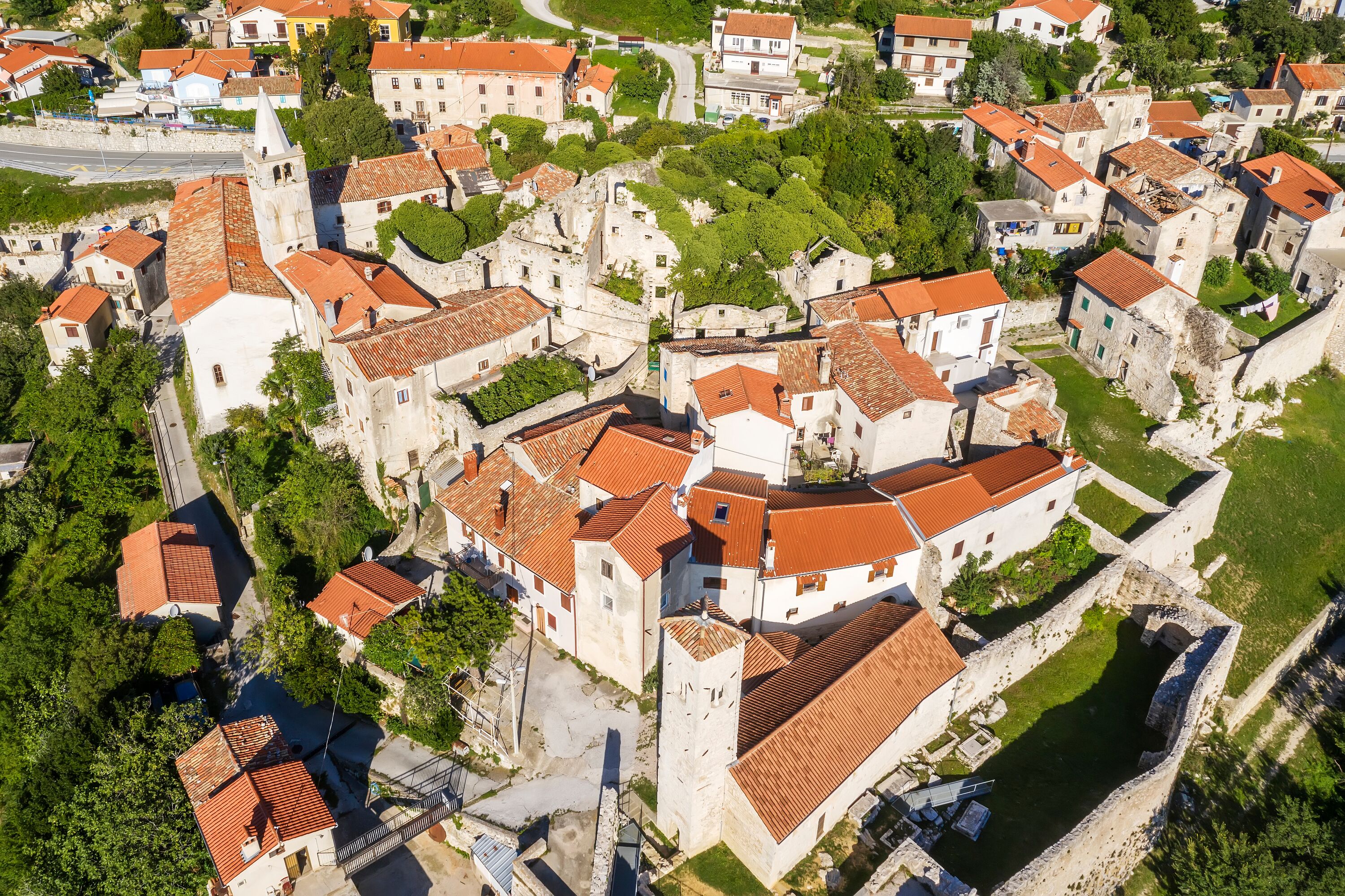 Vista aérea de uma cidade histórica com edifícios bem próximos, ruas estreitas e uma igreja imponente com um campanário.