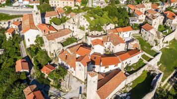 Vista aérea de uma cidade histórica com edifícios bem próximos, ruas estreitas e uma igreja imponente com um campanário.