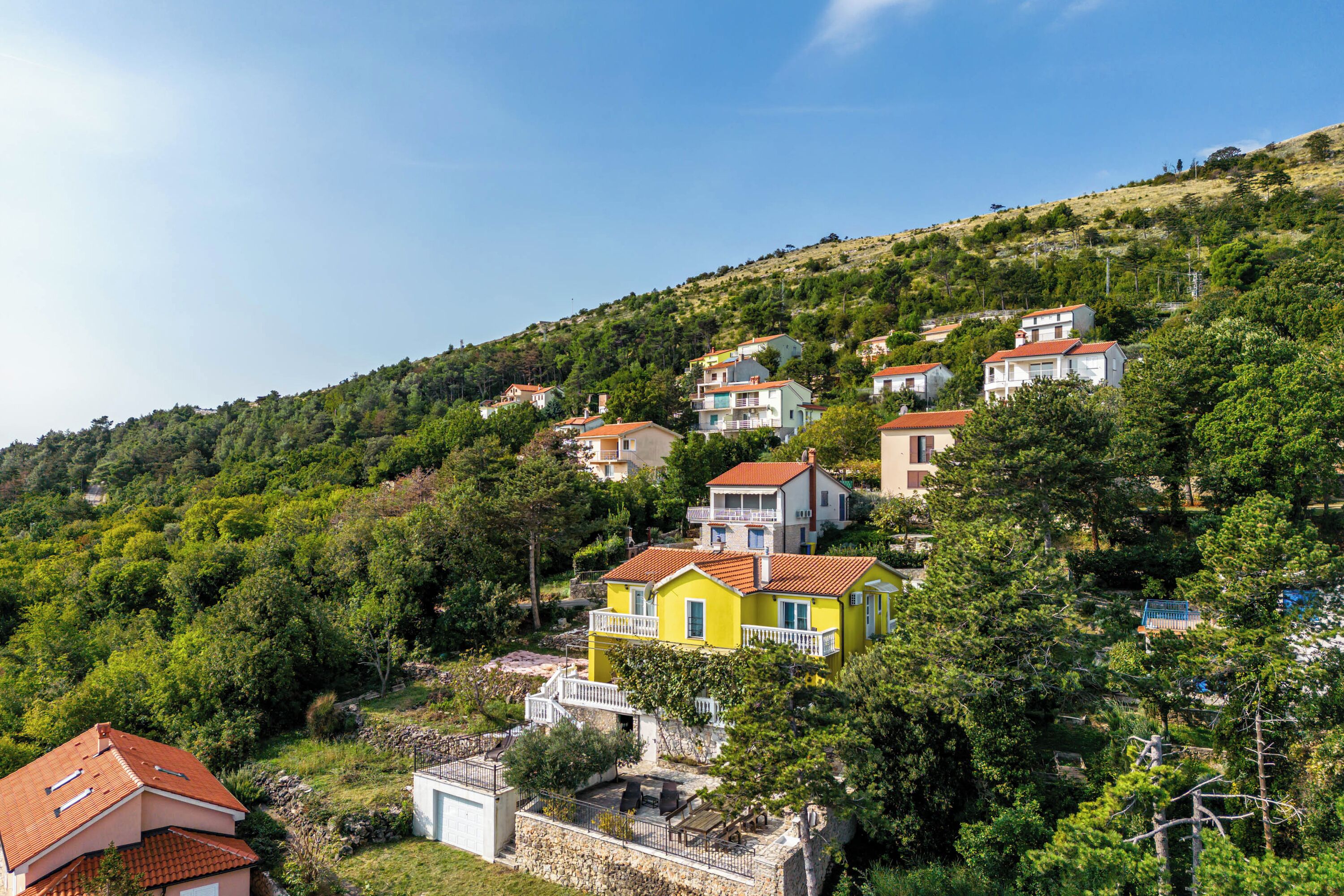 A hillside residential area with houses featuring balconies and red-tiled roofs.