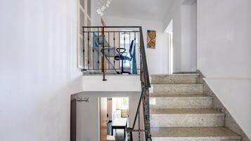 A staircase with a handrail and a door leading to a room with a dining table and chairs.