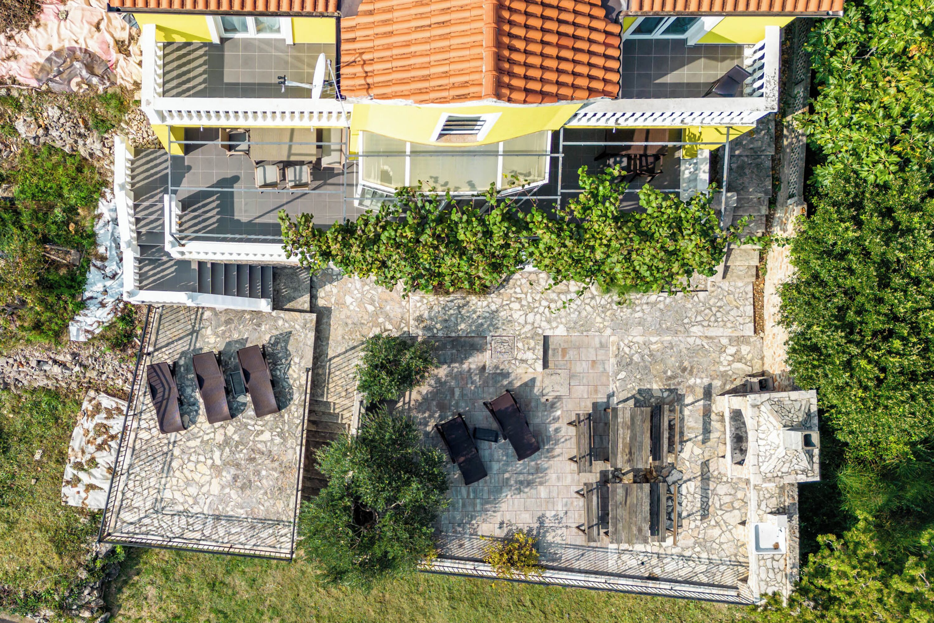 An aerial view of a modern building with a stone patio, outdoor seating, and a stone wall.