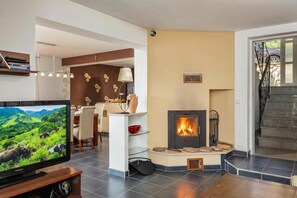 Una sala de estar moderna con televisor, chimenea, comedor y escalera.