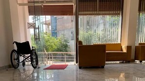 A spacious room with a wheelchair, a red mat, and a sofa. - Earth View Residency  (Noida)