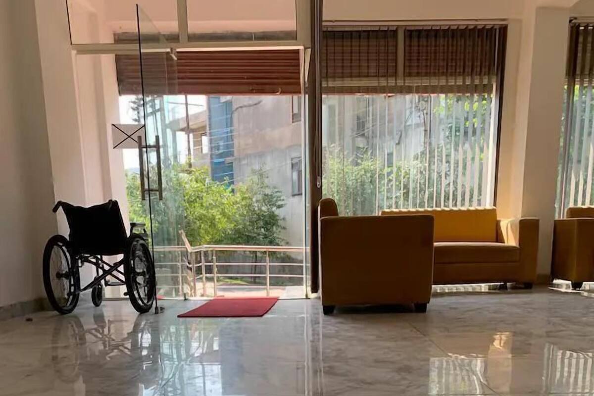 Una habitación amplia con una silla de ruedas, un tapete rojo y un sofá.