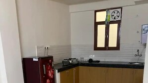 A kitchen with a refrigerator, sink, and cabinets. - Earth View Residency  (Noida)