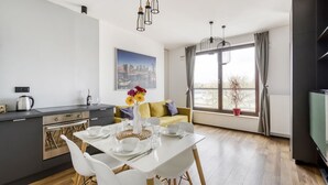 A modern kitchen with a dining area, a sofa, and a large window with a view. - Warsaw Night Apartments Giełdowa (Warsaw)