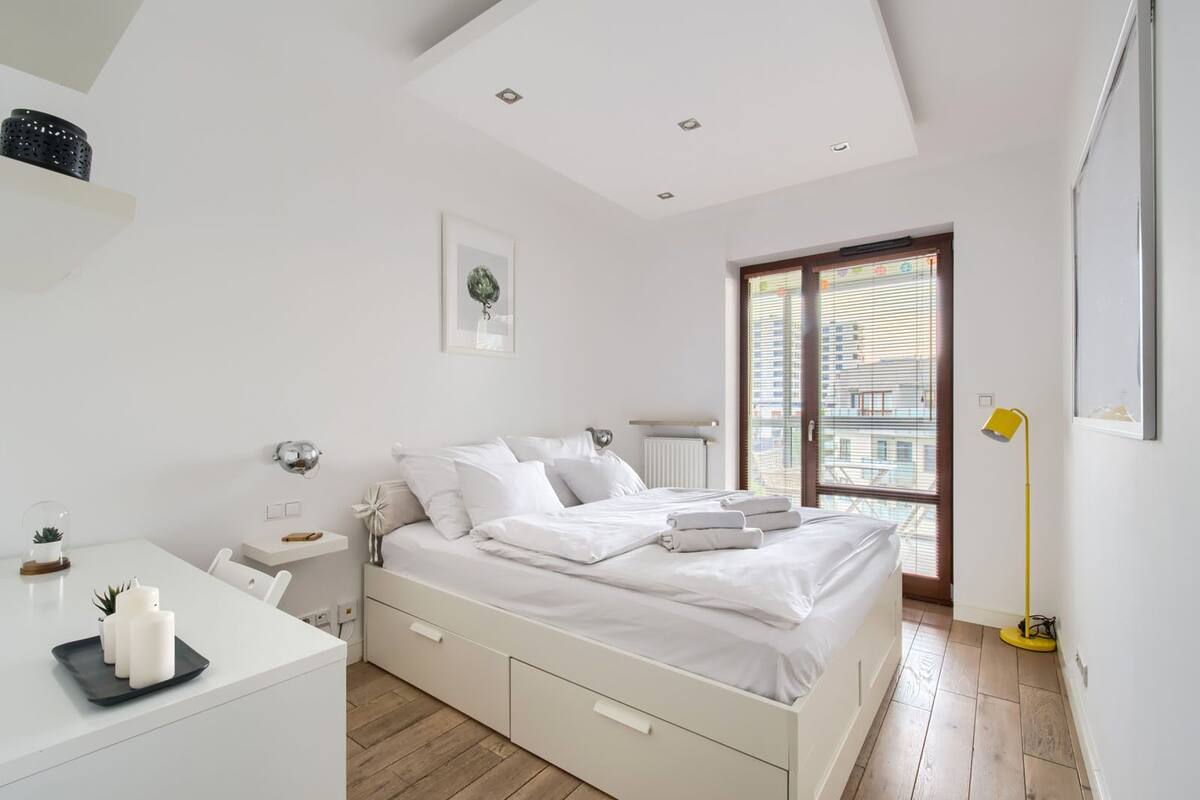 Une chambre moderne avec un lit, des tables de chevet, un bureau et une fenêtre avec des stores.