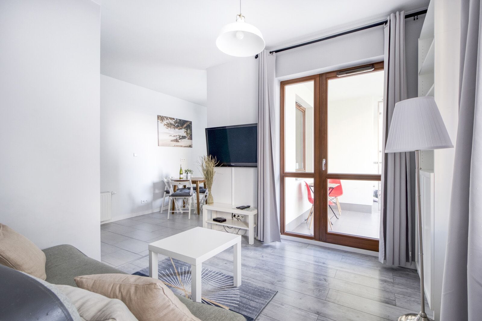 Ein modernes Wohnzimmer mit einer Couch, einem Couchtisch, einem Fernseher und einem Essbereich mit Stühlen und einem Tisch.