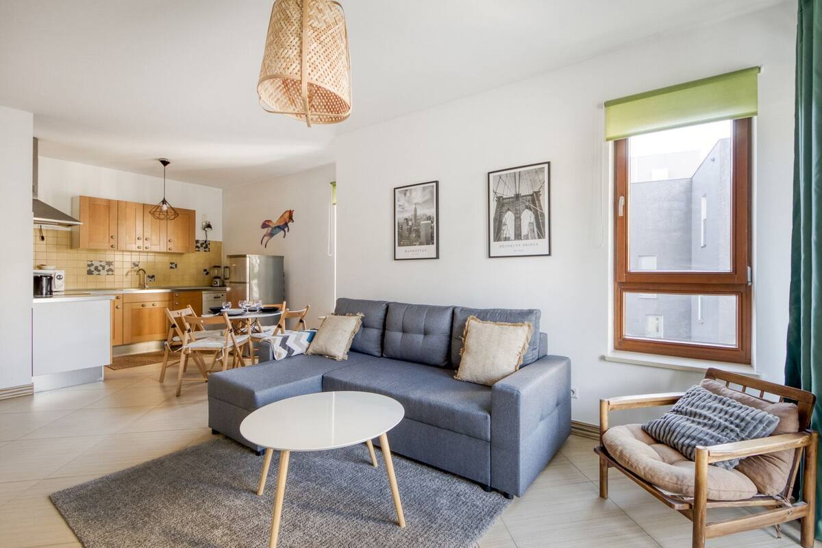 Un salon moderne avec un canapé gris, une table basse ronde et un coin repas comprenant des chaises et une table en bois.