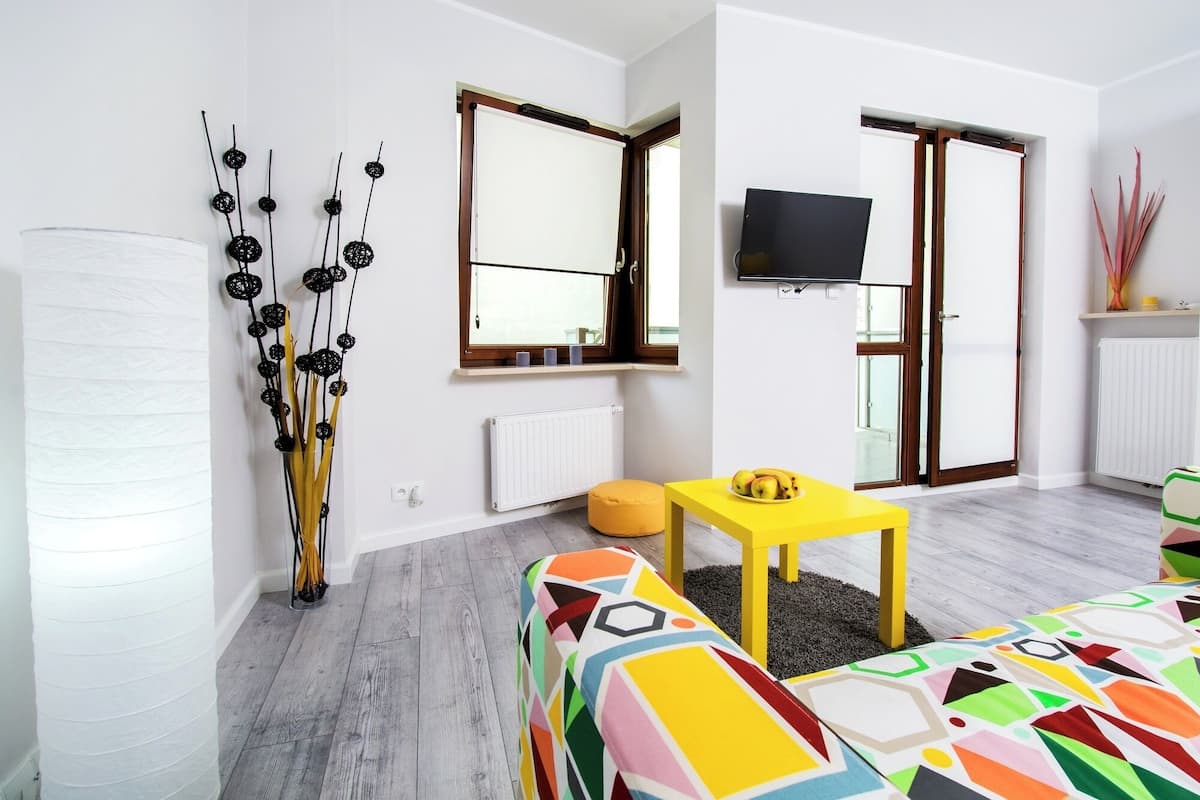 Un salon moderne avec un canapé, une table jaune et un téléviseur.