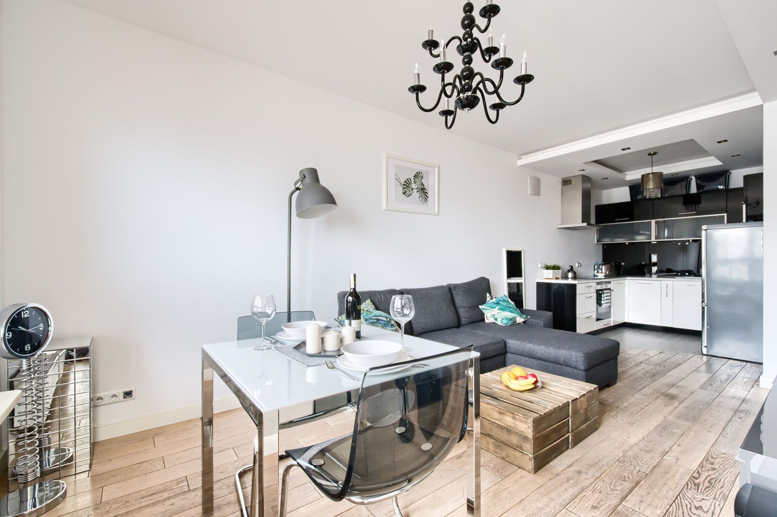 A modern living room with a dining table, sofa, and kitchen area.