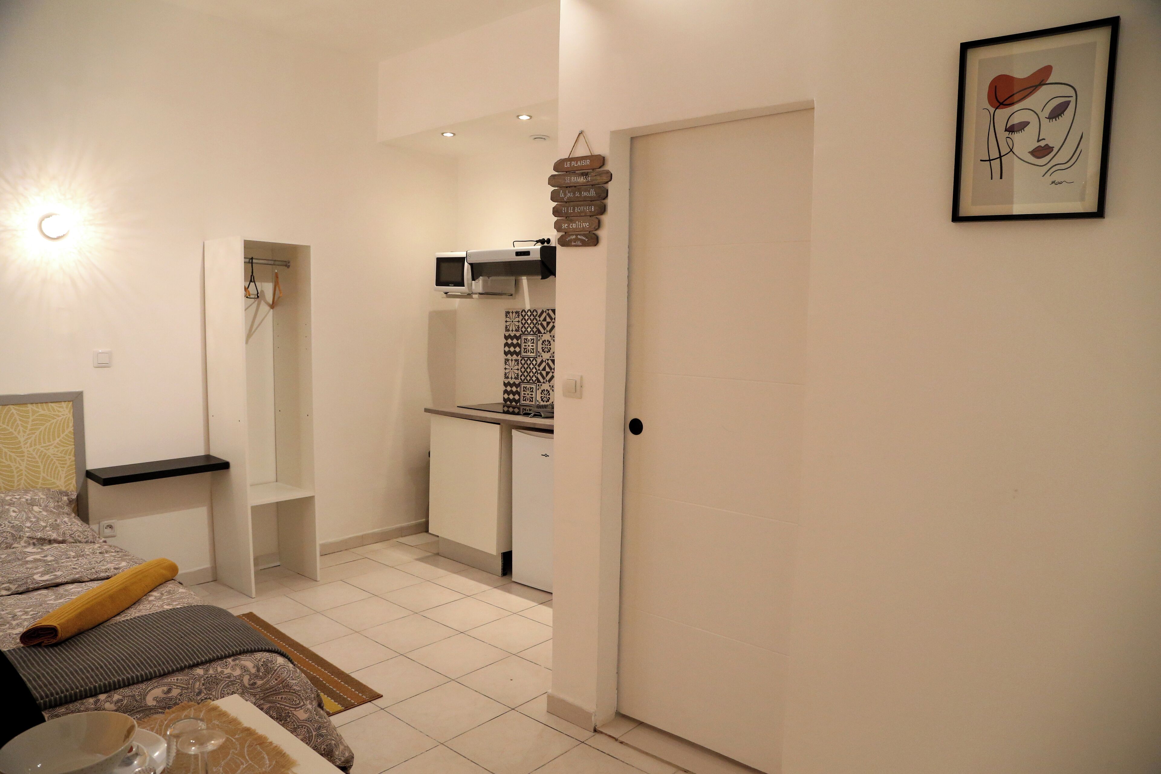 Une pièce de taille modeste comprenant un lit, une petite kitchenette et une salle de bain.