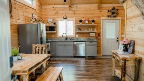 L’intérieur d’une cabane en bois comprend un coin cuisine, des bancs en bois et une table à manger.
