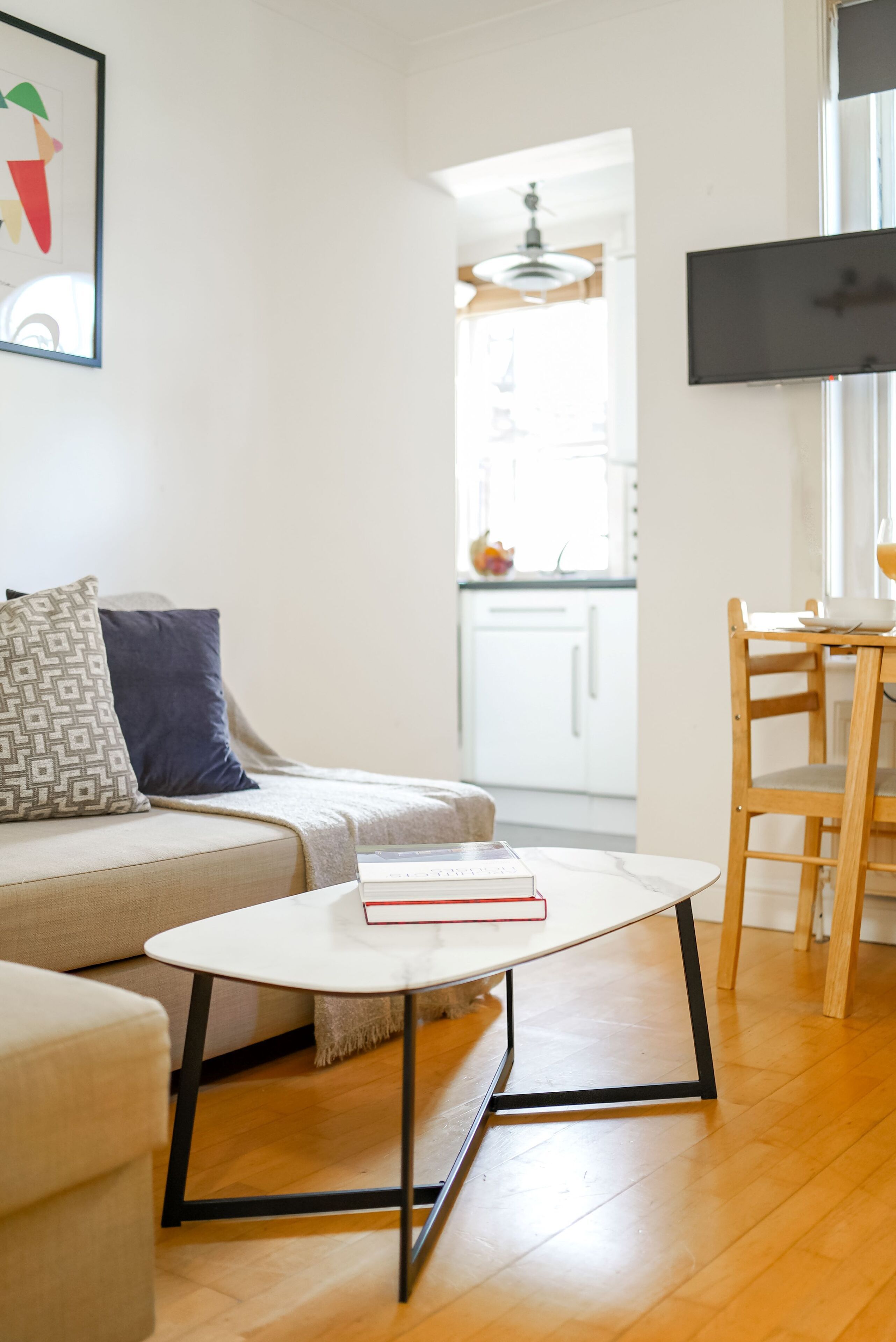 A modern living room with a sofa, a small round table, and a TV mounted on the wall.