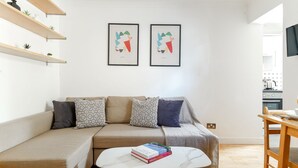 A modern living room with a beige sofa, a white coffee table with books, and two framed artworks above the sofa. - London Flat in the Heart of Fitzrovia (London)