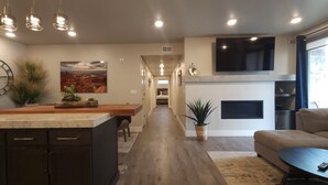 Una cocina moderna con una isla central, iluminación colgante, un reloj grande y un cuadro en la pared.