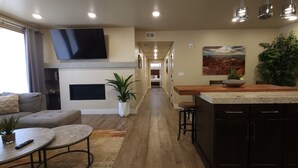 Una cocina moderna con una isla central, un comedor y una sala de estar con sofá y mesa de centro.