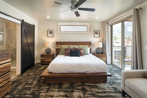 A spacious bedroom with a large bed, wooden headboard, two bedside tables with lamps, a ceiling fan, and a view of the outdoors through a sliding door. - SageCreek at Moab *Combined Two Unit Rental B* (Moab)