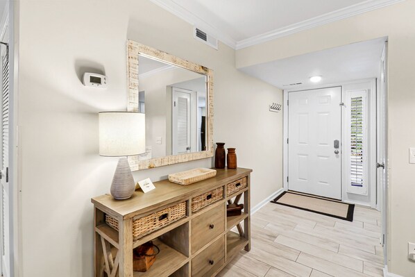 A hallway with a wooden console table, a mirror, a lamp, and a door with a window. - Newly Updated Villa – Short Walk to the Beach! (Hilton Head)