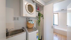 Een compacte keuken met een ingebouwde wasmachine, een spoelbak en een raam.
