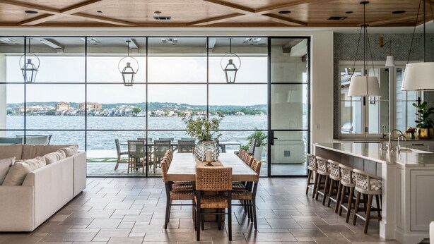 Un comedor amplio con vistas al agua, un sofá blanco y una cocina con taburetes de bar.