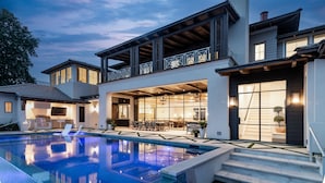 Una casa moderna con piscina, mobiliario exterior y porche cubierto.