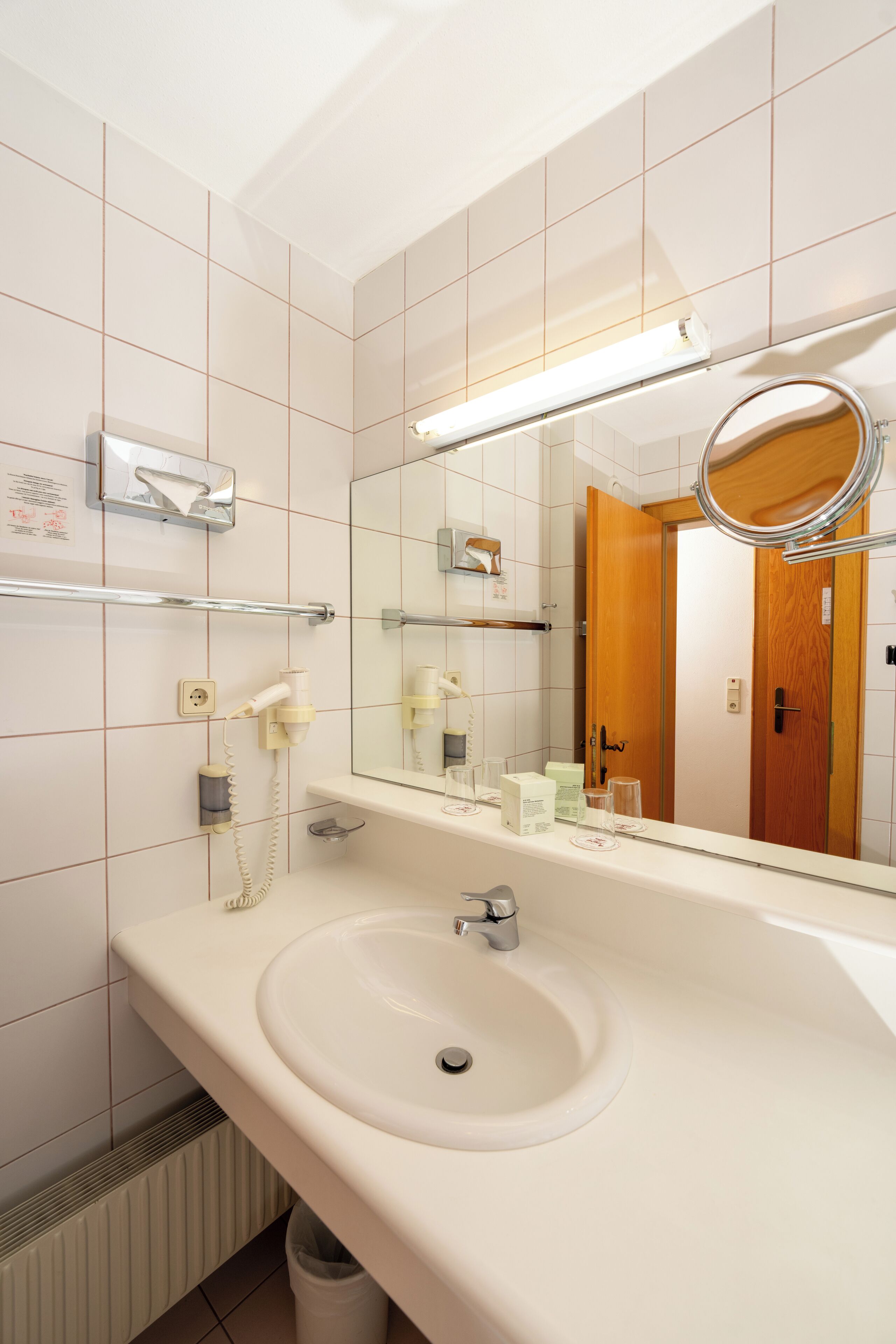 A modern bathroom with a white sink, a mirror, and a towel rack.