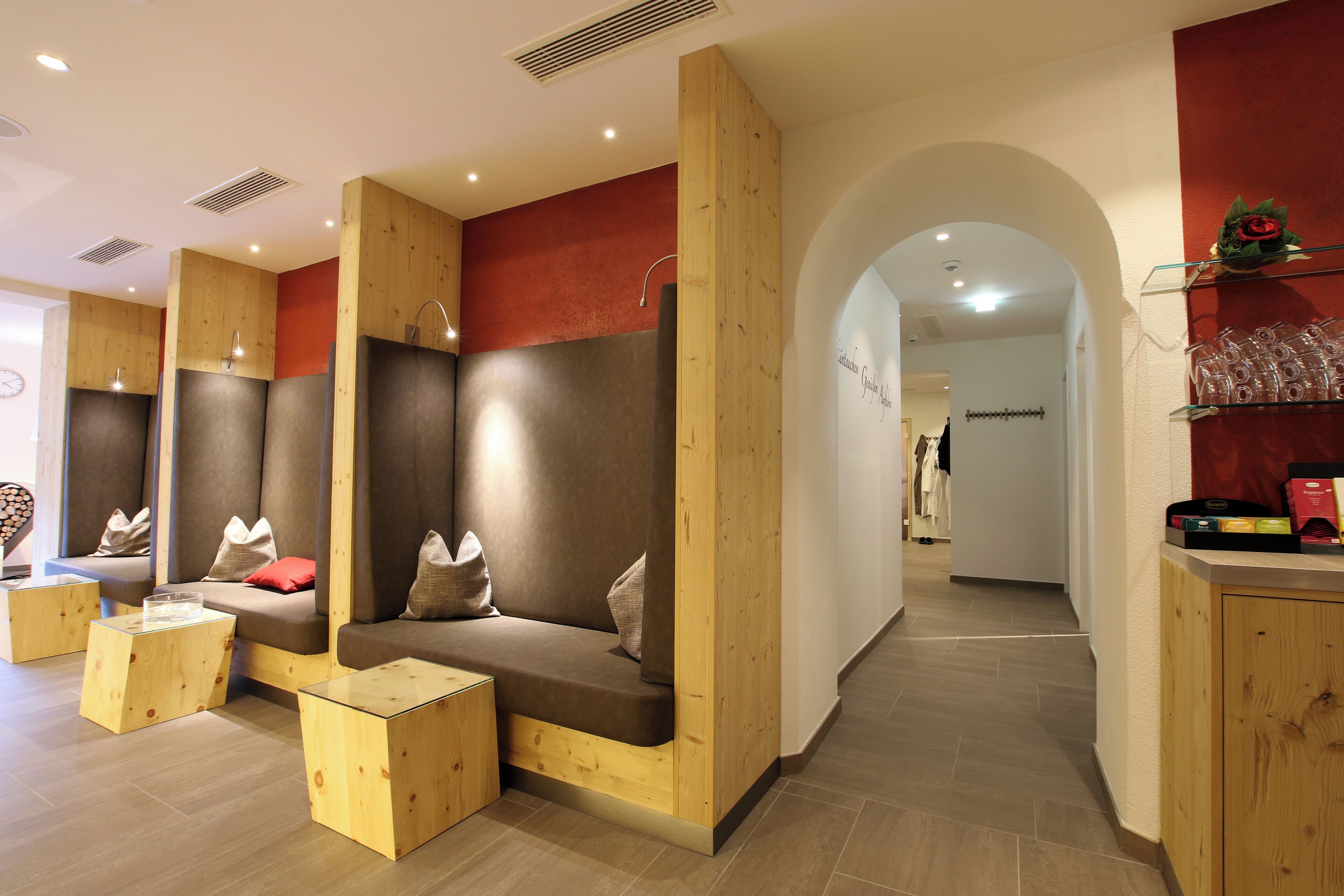 Un espace spa moderne agrémenté d’éléments en bois, un coin salon avec des coussins et un comptoir d’accueil avec des objets en verre.