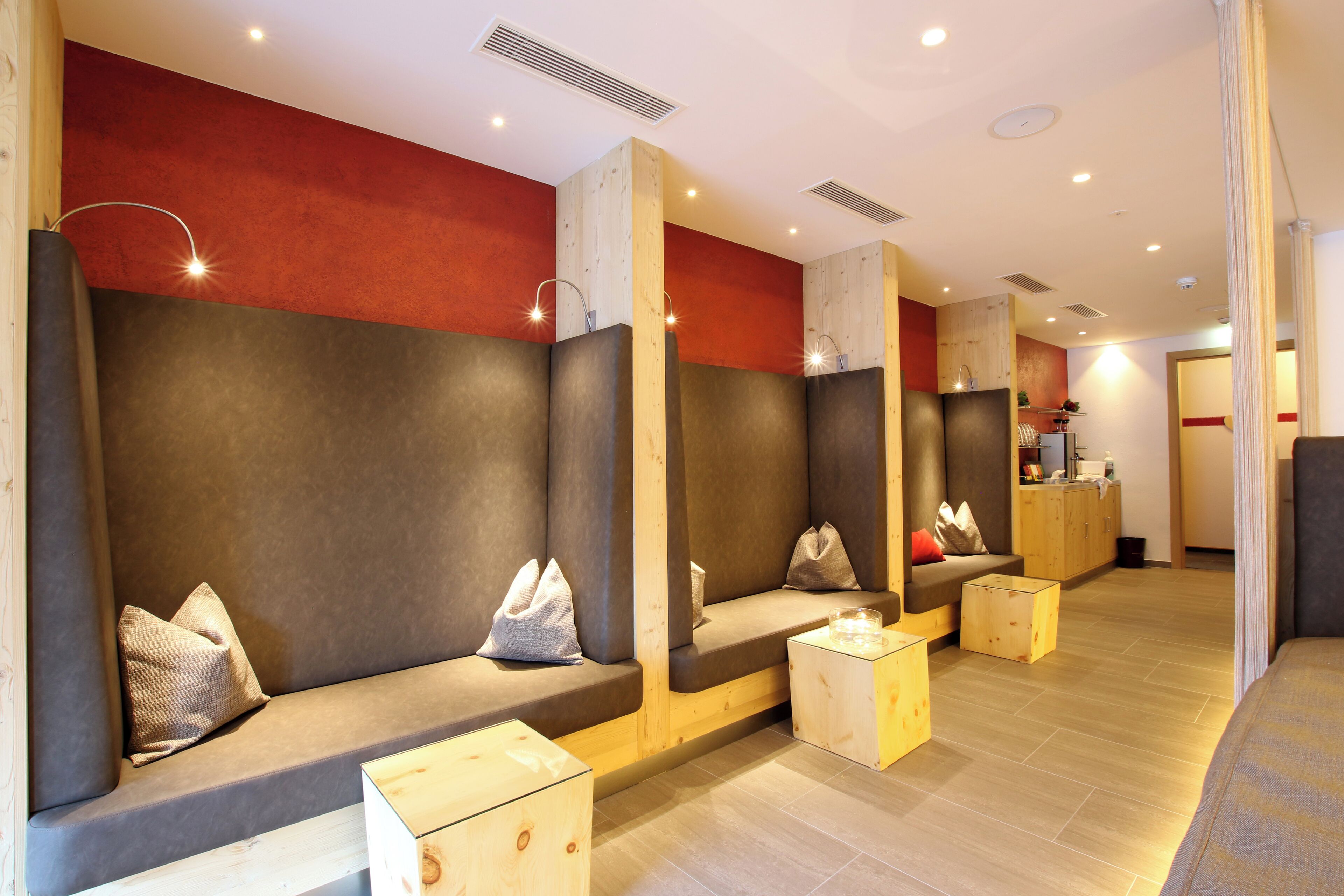 Un espace de spa moderne avec des éléments décoratifs en bois, un comptoir d’accueil et un coin salon agrémenté de coussins.