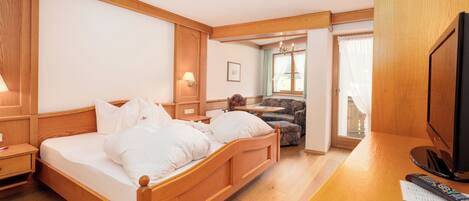 A wooden-framed bedroom with a bed, a desk, a chair, and a television.
