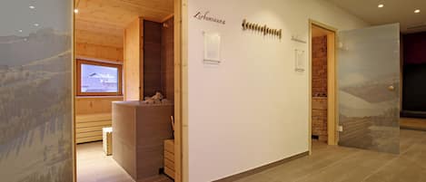 Een receptiegedeelte met een houten receptiebalie, een prikbord en een uitzicht op een bergachtig landschap door een glazen wand.