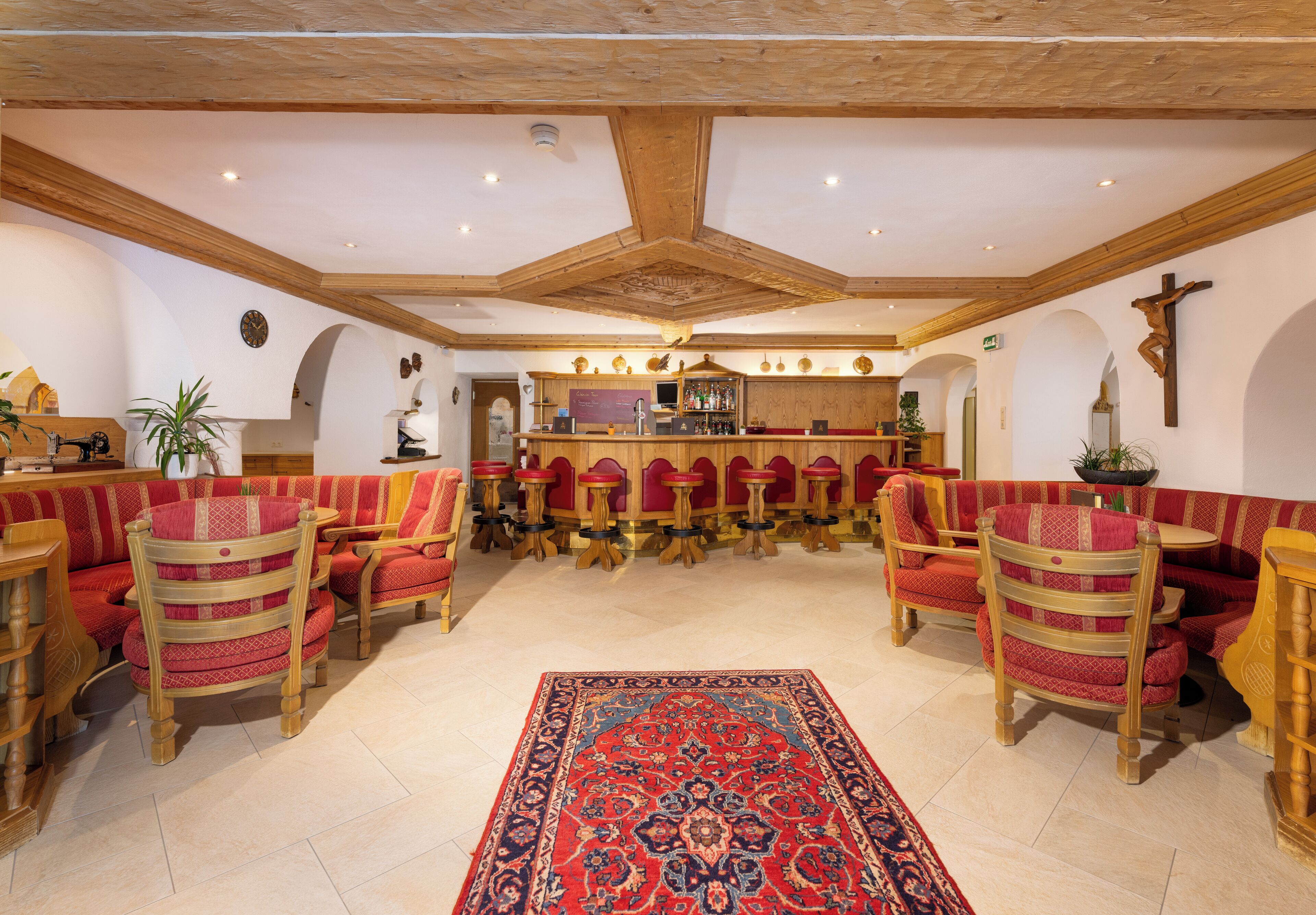 A spacious room with wooden furniture, a patterned rug, and a bar area.