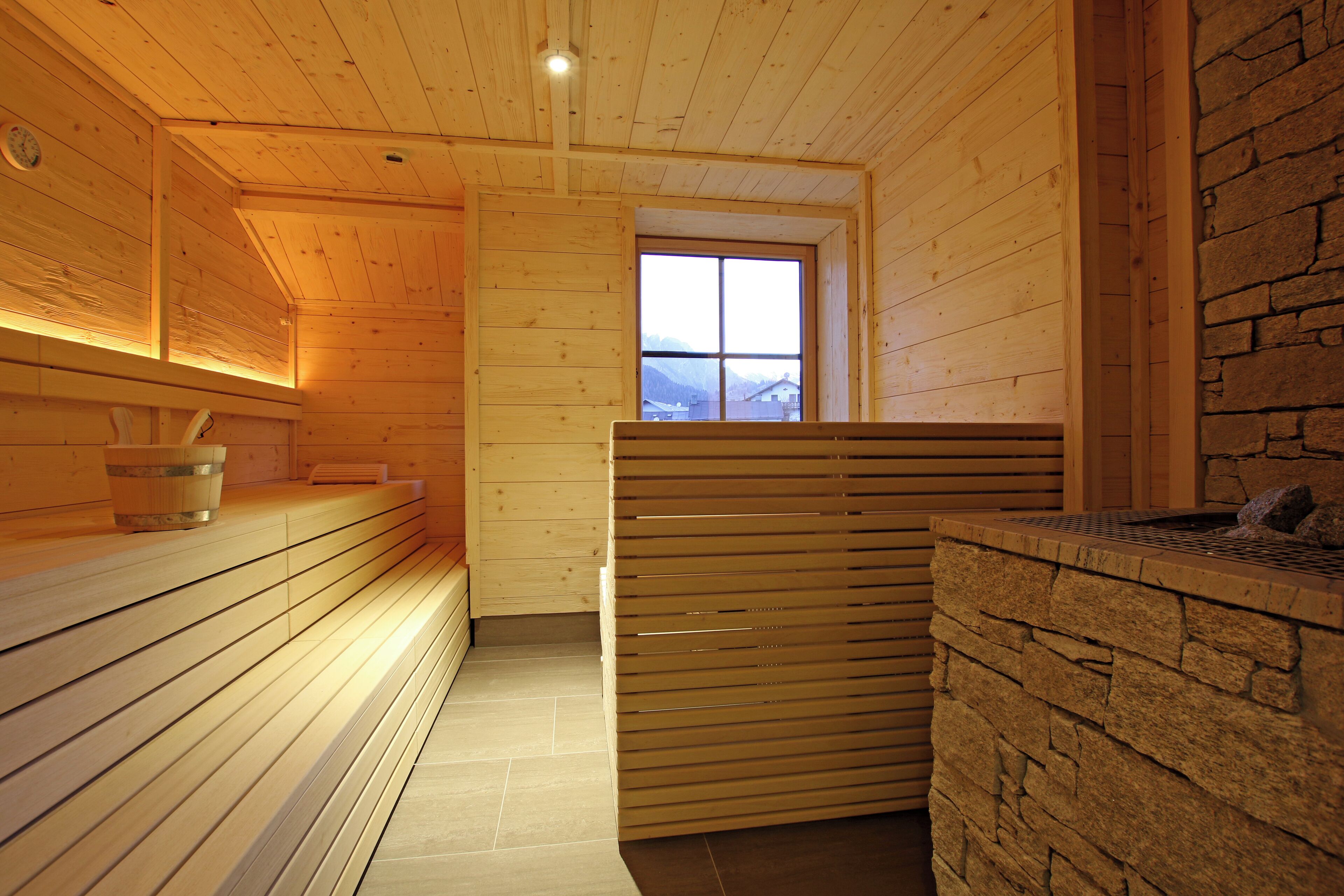 Een houten interieur met een stenen muur, een bank en een raam met uitzicht.