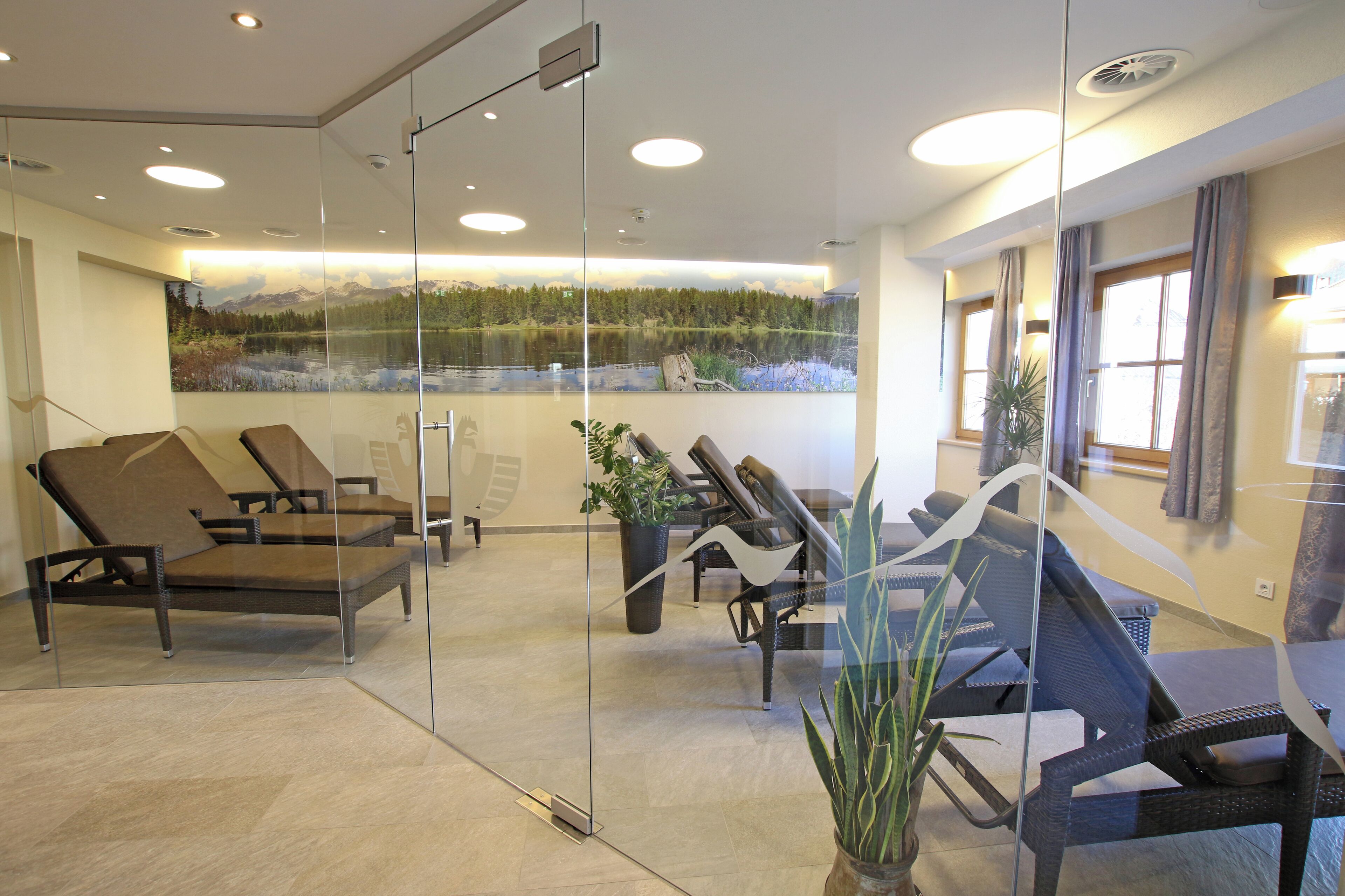 A modern waiting area with glass partitions, comfortable lounge chairs, and a large window with a mountain view.