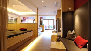 A modern hotel room with a wooden interior, a sofa with red cushions, and a small table. - Schwarzer Adler (Nauders)
